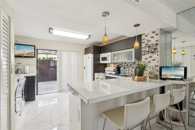 kitchen featuring white appliances, tasteful backsplash, washer and clothes dryer, a peninsula, and marble finish floor