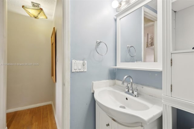 bathroom with baseboards, wood finished floors, and vanity