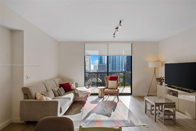 living room with rail lighting, wood finished floors, baseboards, and expansive windows