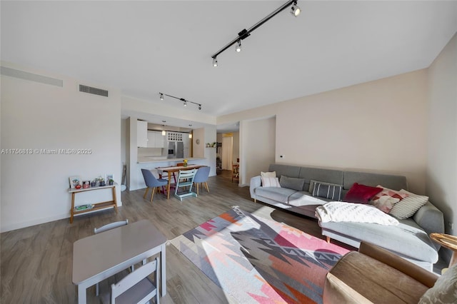 living room featuring visible vents, rail lighting, and wood finished floors