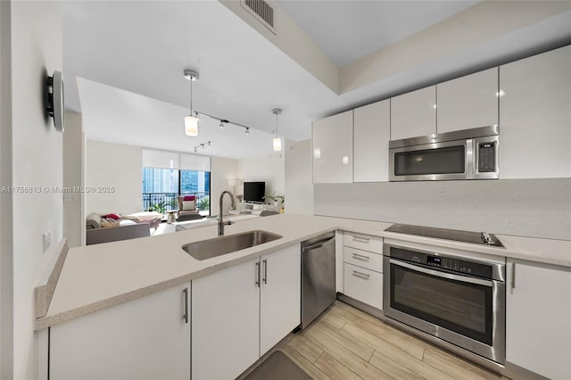 kitchen with light countertops, white cabinets, appliances with stainless steel finishes, and a sink