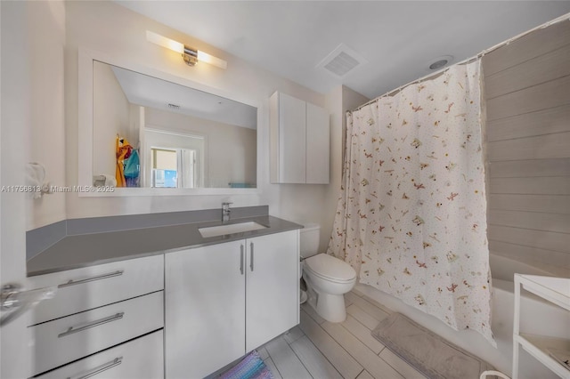 full bathroom with visible vents, toilet, wood finished floors, shower / bath combination with curtain, and vanity