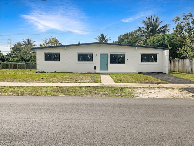 view of front of home featuring stucco siding, a front yard, and fence