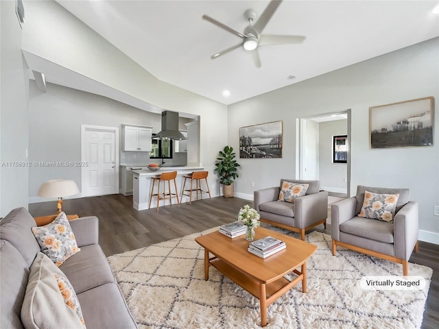 living area with dark wood finished floors, a ceiling fan, and baseboards