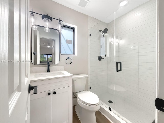 bathroom featuring vanity, toilet, visible vents, and a stall shower