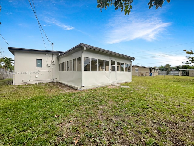 back of house with a lawn, fence, and a sunroom