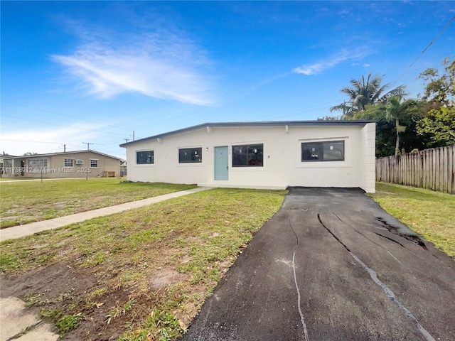 view of front of home with stucco siding, a front yard, and fence