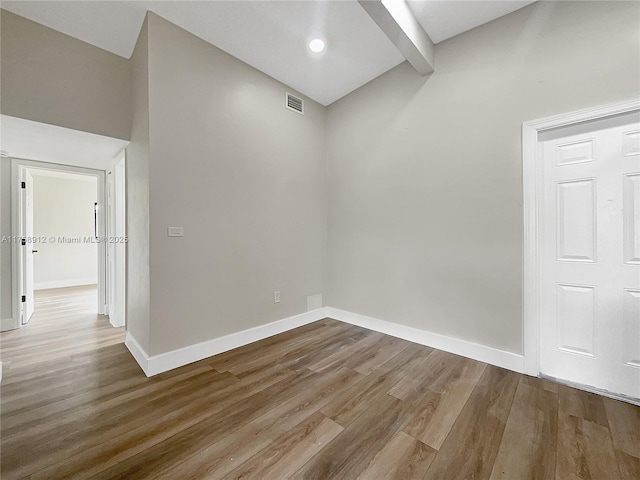 unfurnished room featuring visible vents, baseboards, beamed ceiling, and wood finished floors