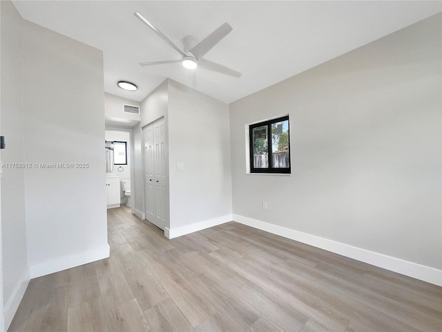 spare room with light wood finished floors, visible vents, a ceiling fan, and baseboards