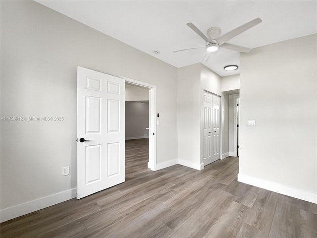 spare room with a ceiling fan, wood finished floors, and baseboards