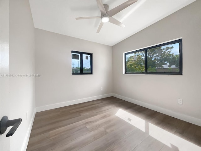 unfurnished room featuring a ceiling fan, lofted ceiling, baseboards, and wood finished floors