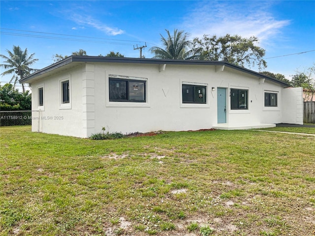 view of front of house featuring stucco siding, a front yard, and fence