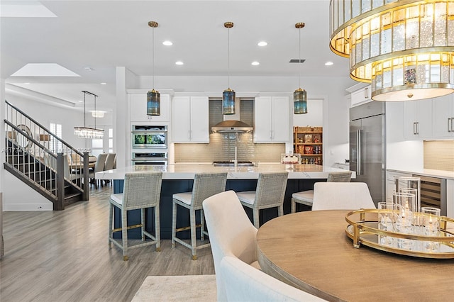 dining space with recessed lighting, a towering ceiling, visible vents, light wood-style floors, and stairway