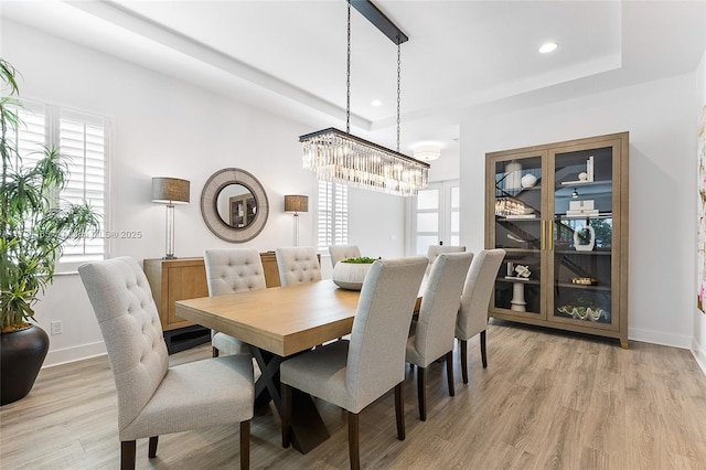 dining room with baseboards, light wood finished floors, a raised ceiling, and recessed lighting