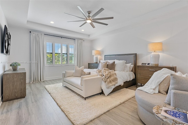 bedroom with baseboards, wood finished floors, a raised ceiling, and recessed lighting