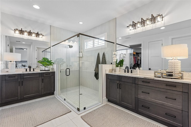 full bathroom featuring a sink, a shower stall, two vanities, and tile patterned flooring