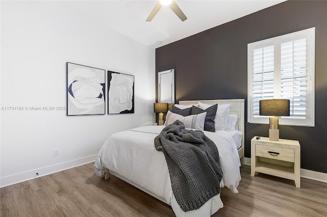 bedroom with a ceiling fan, baseboards, and wood finished floors