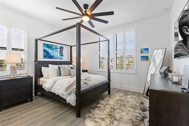 bedroom with a ceiling fan, light wood-style flooring, and baseboards