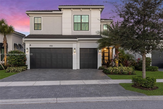 view of front of house featuring an attached garage, a tiled roof, decorative driveway, and stucco siding