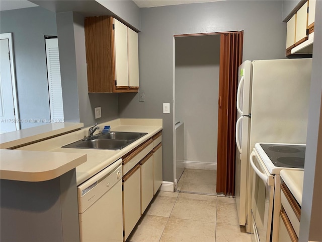 kitchen featuring light tile patterned floors, white appliances, a sink, baseboards, and light countertops