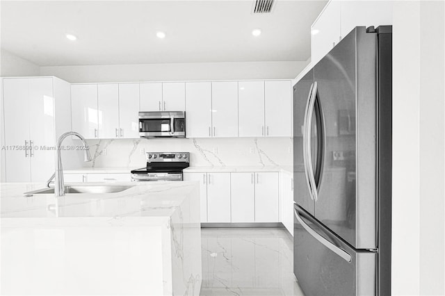 kitchen with appliances with stainless steel finishes, white cabinets, visible vents, and a sink