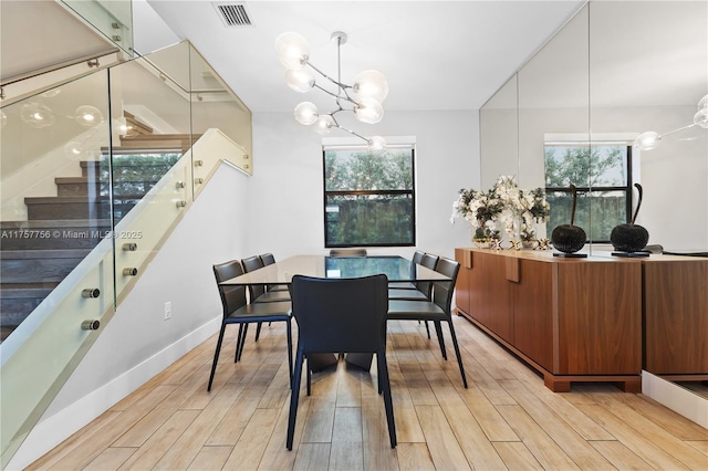 dining room featuring stairway, visible vents, light wood finished floors, and a chandelier