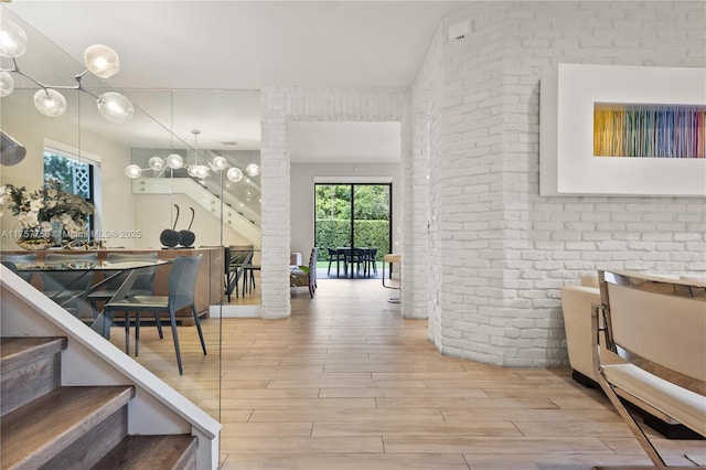 interior space with an inviting chandelier, wood finished floors, and brick wall