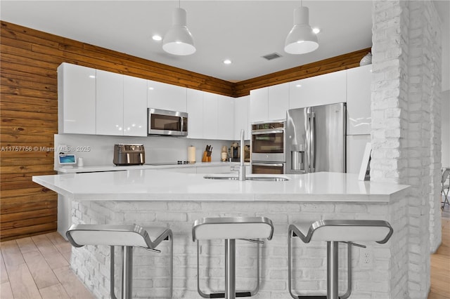 kitchen featuring modern cabinets, a kitchen bar, appliances with stainless steel finishes, and white cabinetry