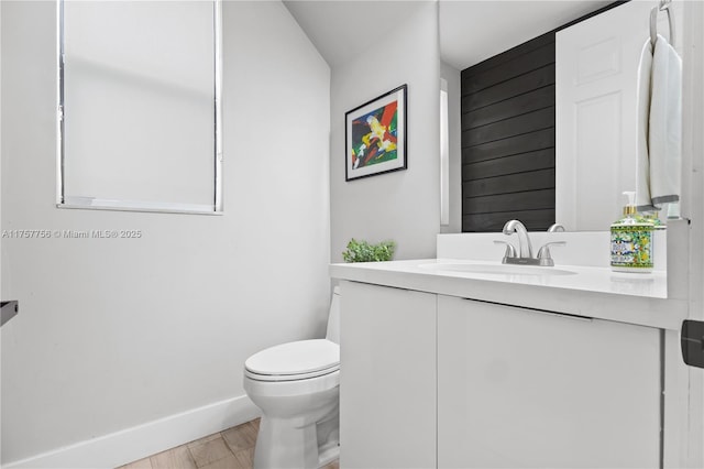 bathroom featuring toilet, vanity, baseboards, and wood finished floors