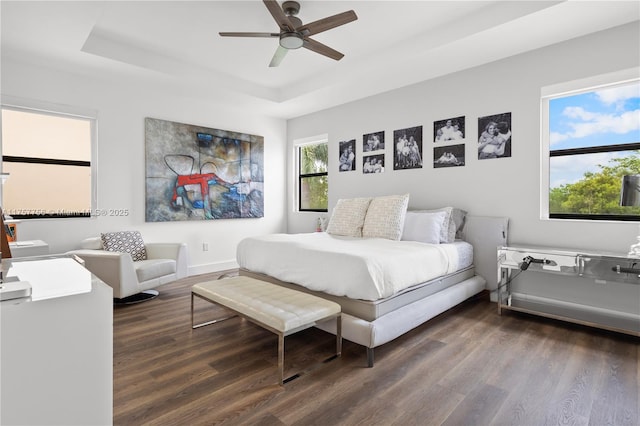 bedroom with ceiling fan, baseboards, a raised ceiling, and wood finished floors