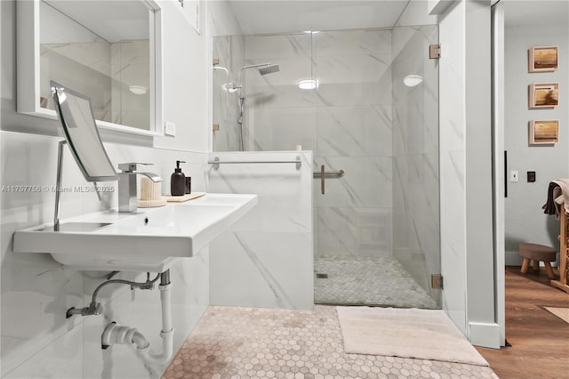 full bath featuring backsplash, wood finished floors, a marble finish shower, and a sink