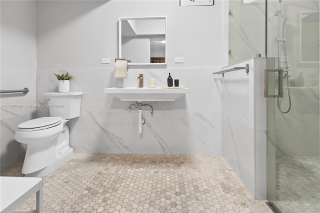 bathroom with a marble finish shower, toilet, and a sink