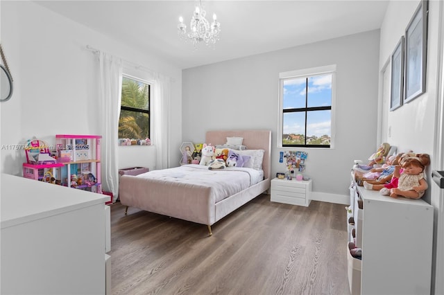 bedroom with a notable chandelier, light wood-type flooring, and baseboards