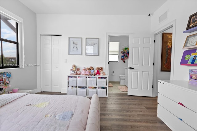 bedroom featuring a closet, visible vents, ensuite bathroom, and dark wood-style flooring