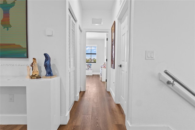 hallway with visible vents, baseboards, and wood finished floors