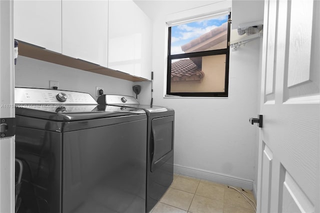 washroom featuring light tile patterned floors, baseboards, cabinet space, and washing machine and clothes dryer