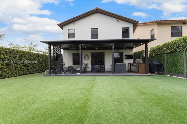 rear view of property featuring a ceiling fan, a fenced backyard, stucco siding, a tiled roof, and a lawn