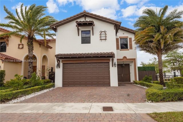 mediterranean / spanish-style home with stucco siding, a tiled roof, and decorative driveway