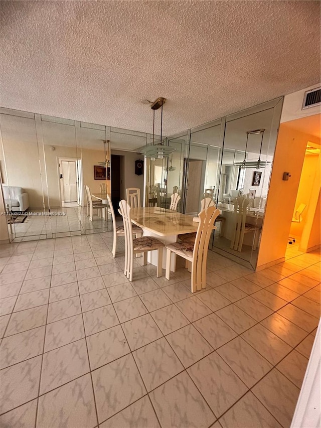 unfurnished dining area featuring light tile patterned flooring, visible vents, and a textured ceiling