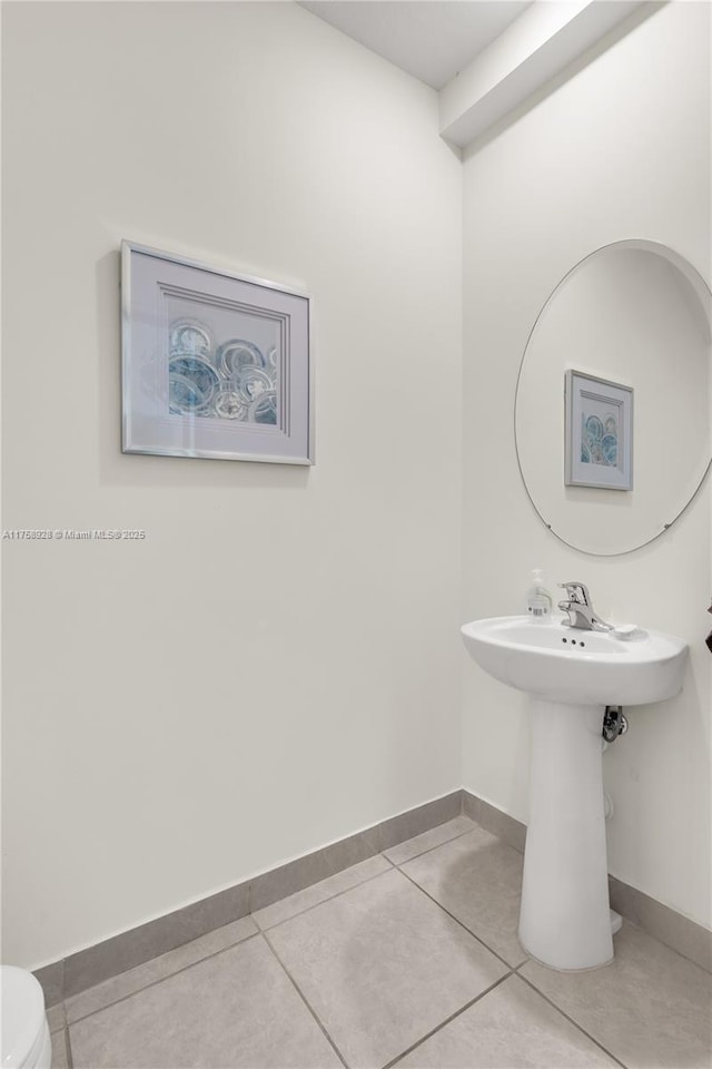 bathroom with baseboards, toilet, and tile patterned floors