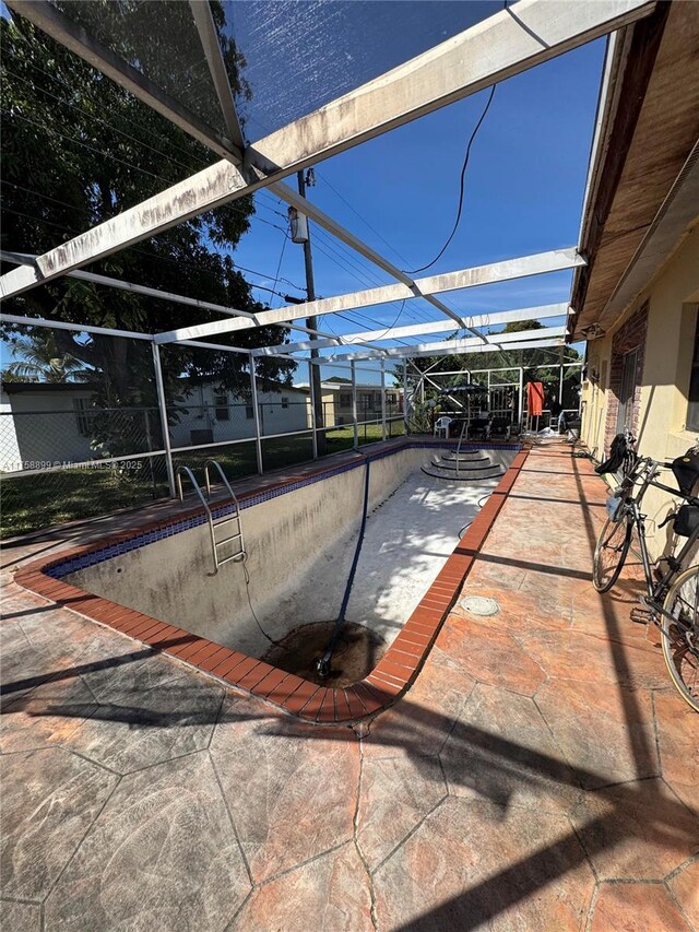 view of patio with an empty pool and glass enclosure