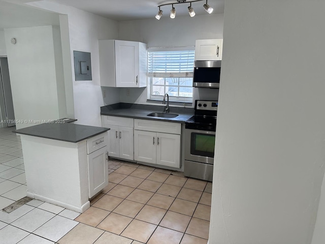 kitchen featuring light tile patterned floors, electric panel, dark countertops, appliances with stainless steel finishes, and a sink