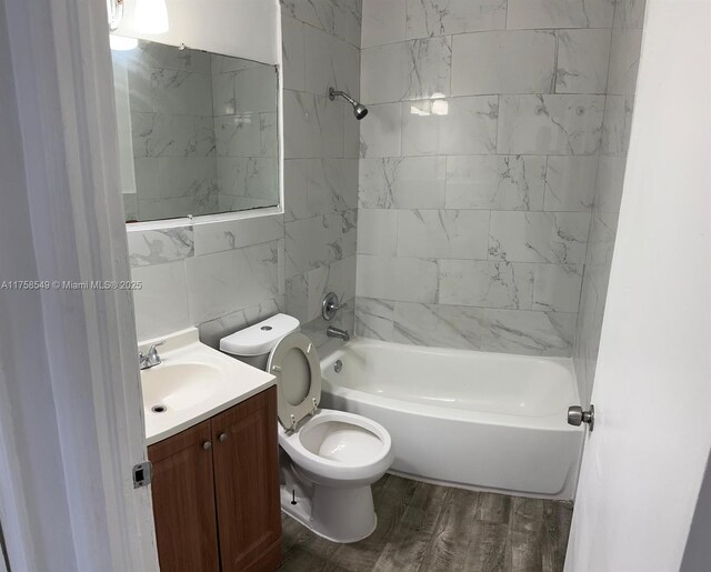 bathroom with toilet, shower / washtub combination, wood finished floors, and vanity