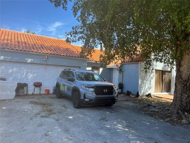 view of home's exterior featuring driveway, a tile roof, and stucco siding