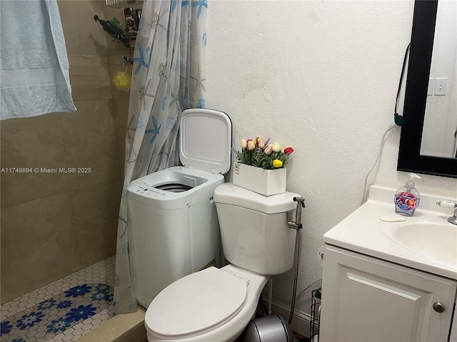 bathroom featuring a stall shower, a textured wall, vanity, and toilet