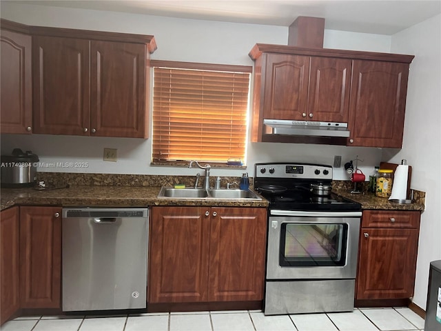 kitchen with appliances with stainless steel finishes, a sink, under cabinet range hood, and dark stone countertops