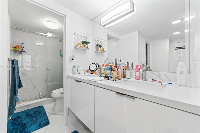 bathroom featuring marble finish floor, a marble finish shower, double vanity, toilet, and a sink