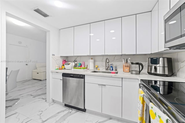 kitchen featuring visible vents, appliances with stainless steel finishes, marble finish floor, light countertops, and a sink