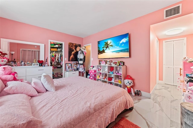 bedroom featuring marble finish floor, a closet, visible vents, a spacious closet, and baseboards