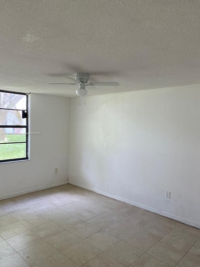 spare room featuring a textured ceiling, baseboards, and a ceiling fan